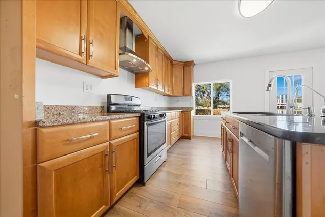 a kitchen with stainless steel appliances granite countertop a sink and a stove