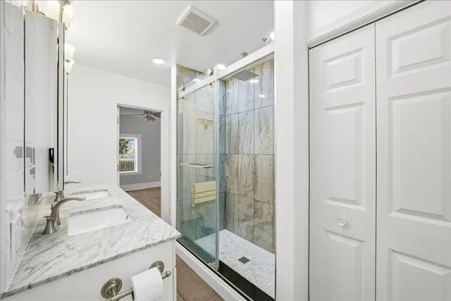 a bathroom with a granite countertop sink a mirror and shower