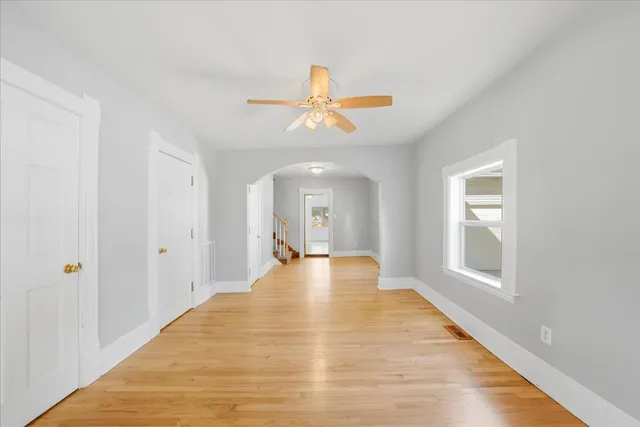 a view of empty room with wooden floor and fan