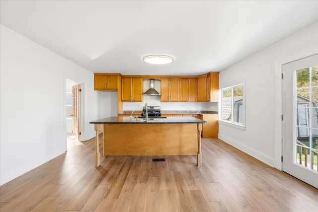 a living room with kitchen island granite countertop wooden floor stainless steel appliances and dining table
