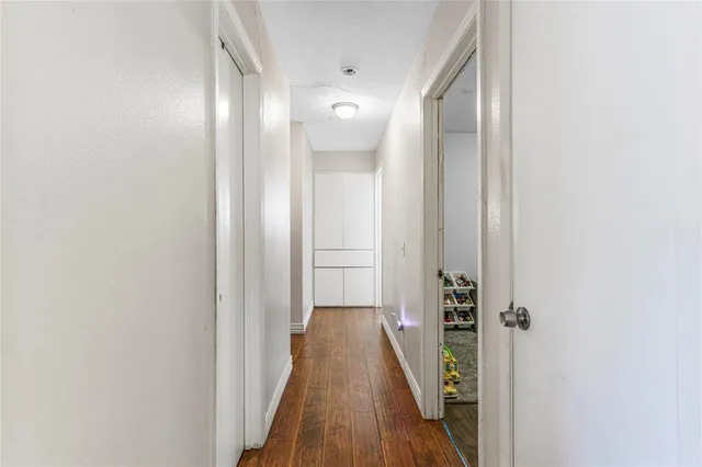 a view of a hallway with wooden floor and a bathroom