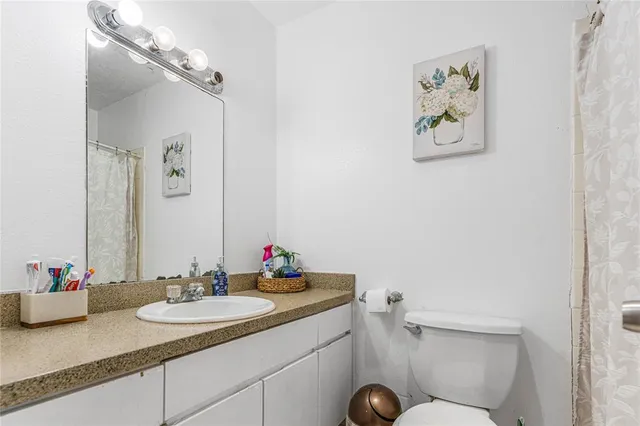 a bathroom with a granite countertop sink a toilet and a mirror