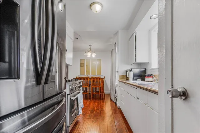 a kitchen with stainless steel appliances a refrigerator a stove a sink and dishwasher with wooden floor