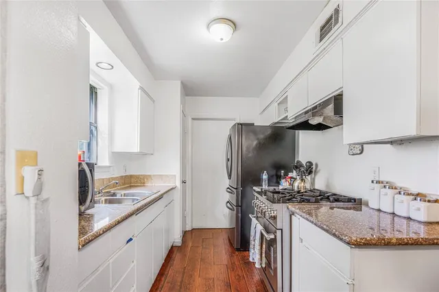 a kitchen with granite countertop a sink stove and refrigerator
