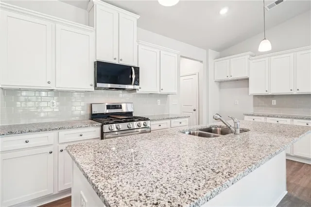 a kitchen with stainless steel appliances granite countertop a sink stove and cabinets