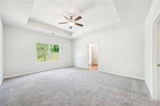 an empty room with ceiling fan and windows