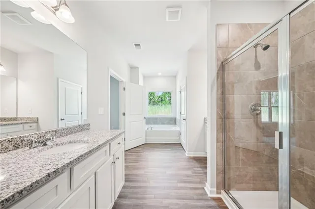 a bathroom with a granite countertop sink a large mirror and a bathtub