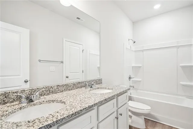 a bathroom with a granite countertop toilet a sink and a bathtub
