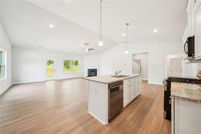 a kitchen with granite countertop a sink a counter space appliances and cabinets