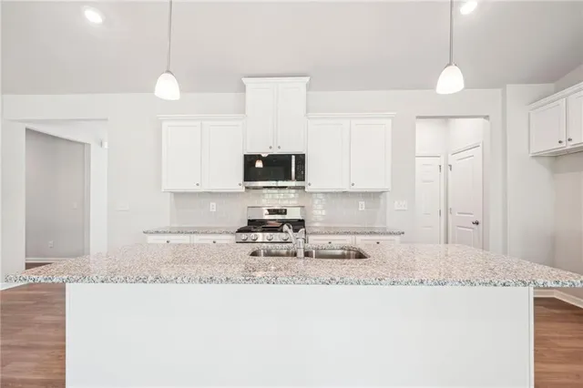 a kitchen with granite countertop a sink stove and white cabinets