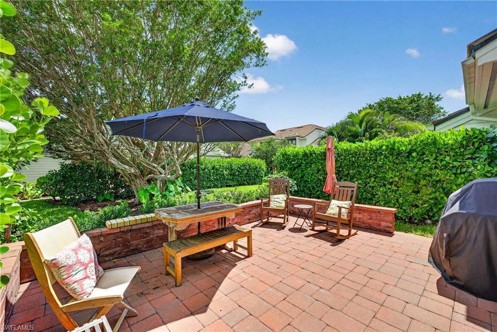 4030 Crayton Road, Unit C2 Naples, FL 34103 - Photo 31 of 32 a backyard of a house with table and chairs under an umbrella