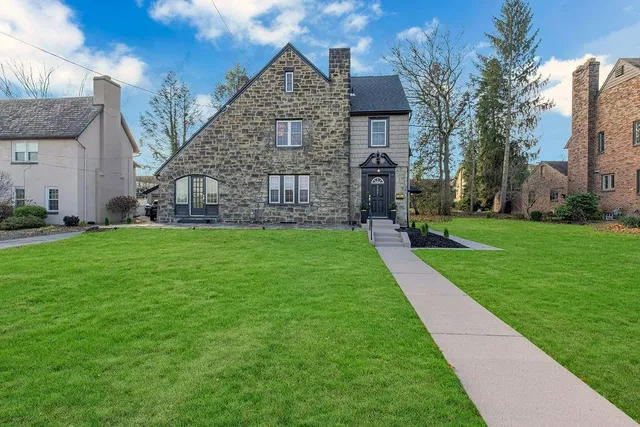 a view of a brick house next to a yard with big trees