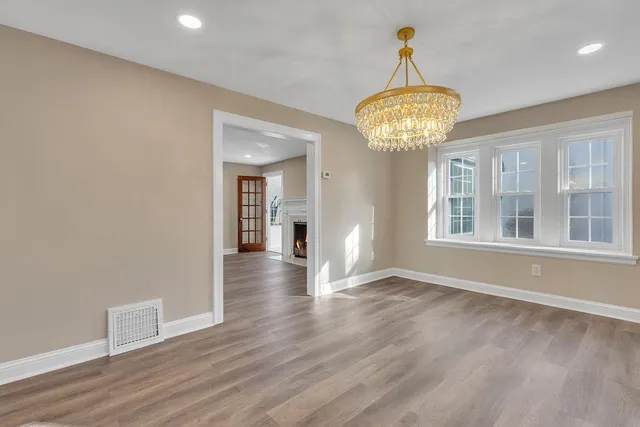 a view of a room with wooden floor chandelier and windows