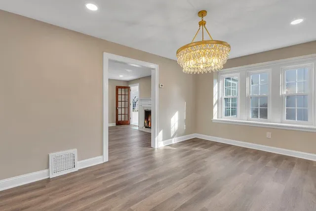 a view of a room with wooden floor chandelier and windows
