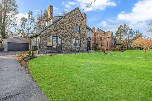 a view of a big house with a big yard and large trees