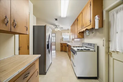 a kitchen with stainless steel appliances granite countertop a refrigerator a stove and a sink