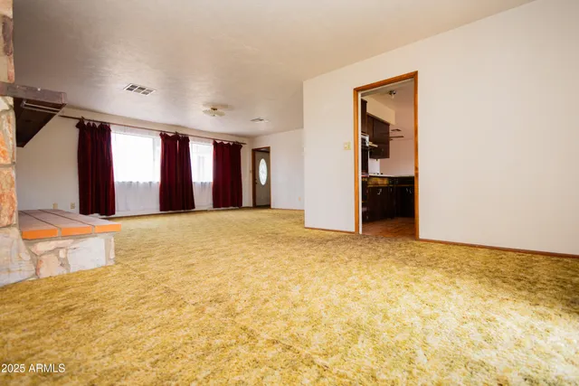 a view of an empty room with window and a kitchen