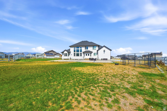 3644 Spiral Springs Road Tooele, UT 84074 - Photo 36 of 41 Expansive backyard with a manicured lawn, white fencing, and a large custom enclosure