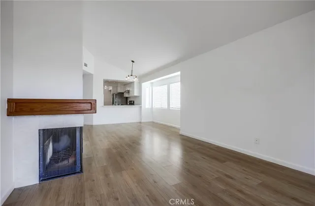 a view of an empty room with wooden floor and a fireplace