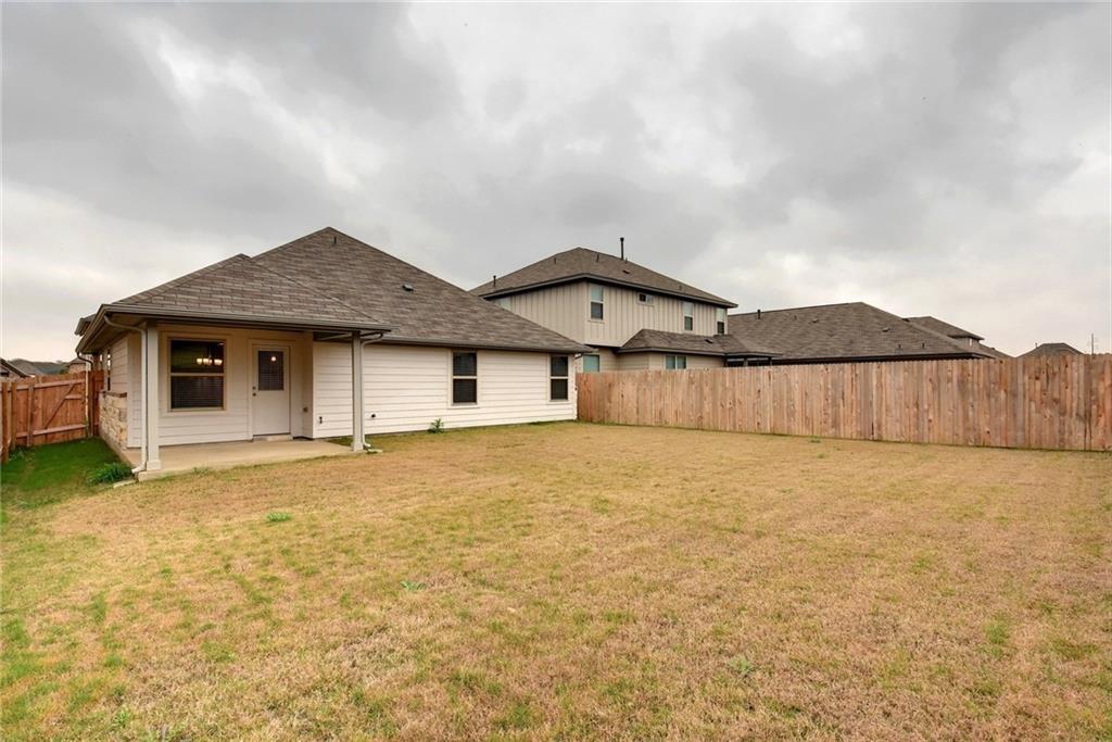 13216 Mariscan Street Manchaca, TX 78652 - Photo 20 of 28 Rear view of house featuring a fenced backyard, a patio area, and roof with shingles