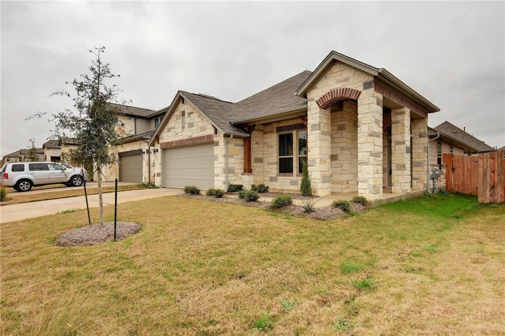13216 Mariscan Street Manchaca, TX 78652 - Photo 26 of 28 View of front facade with stone siding, driveway, a garage, and a shingled roof
