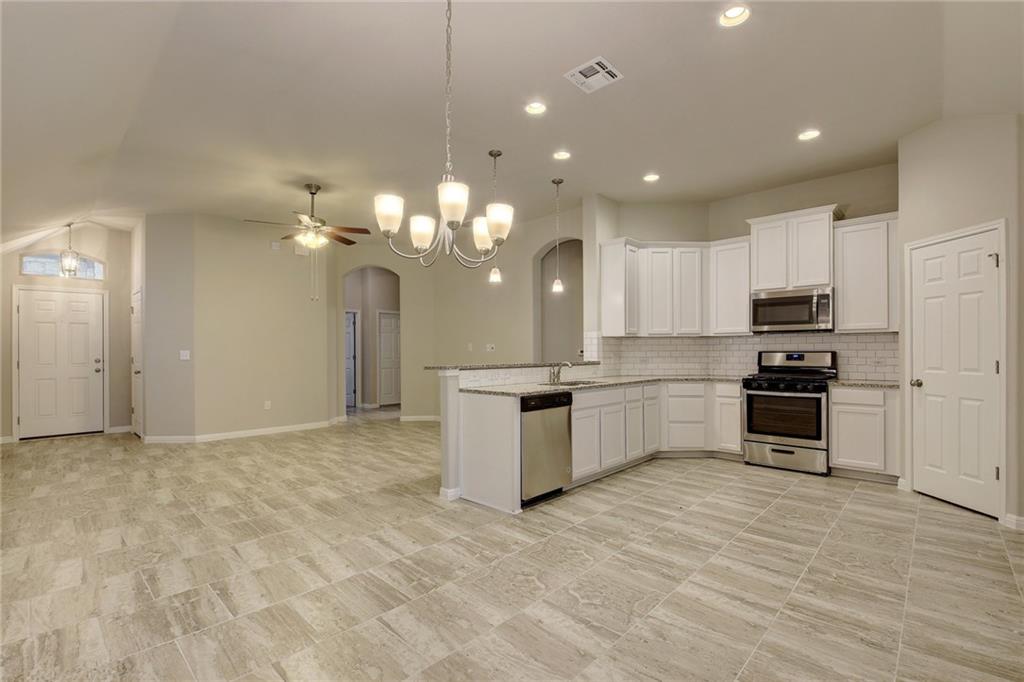 13216 Mariscan Street Manchaca, TX 78652 - Photo 27 of 28 Kitchen featuring white cabinets, stainless steel appliances, open floor plan, a chandelier, and arched walkways