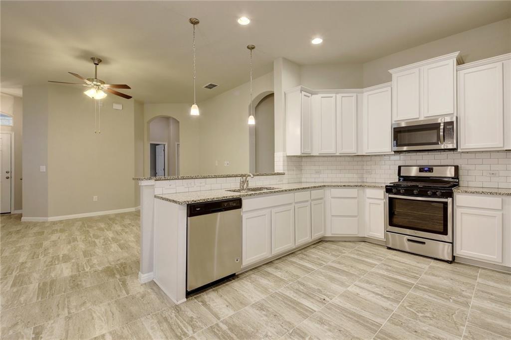 13216 Mariscan Street Manchaca, TX 78652 - Photo 8 of 28 Kitchen with stainless steel appliances, white cabinetry, decorative light fixtures, light stone countertops, and a ceiling fan