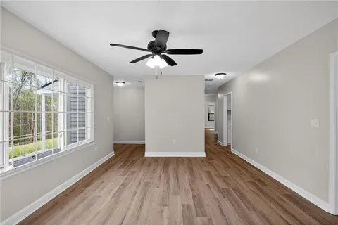 a view of an empty room with wooden floor and a window
