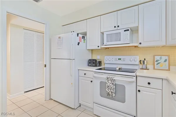 a kitchen with white cabinets and white appliances