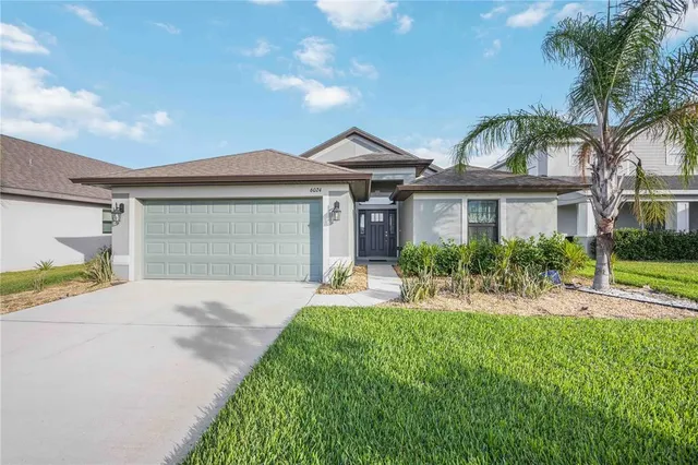 a front view of a house with a yard and potted plants