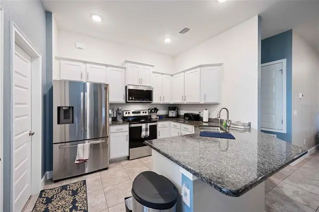 a kitchen with granite countertop a refrigerator a stove and a sink with wooden floor