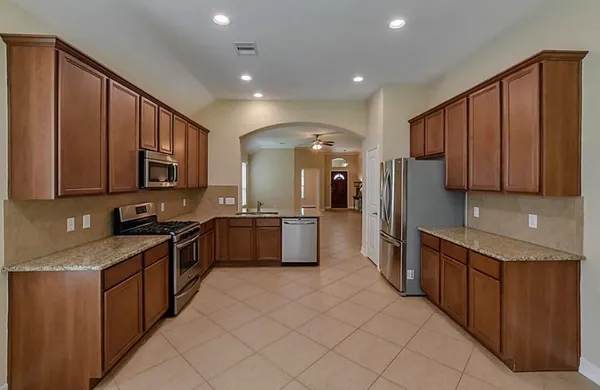 a large kitchen with stainless steel appliances wooden cabinets a sink and a stove