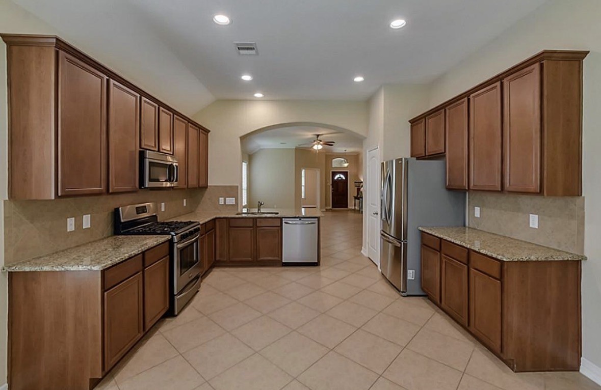 16710 Dover Mills Drive Spring, TX 77379 - Photo 6 of 15 a large kitchen with stainless steel appliances wooden cabinets a sink and a stove