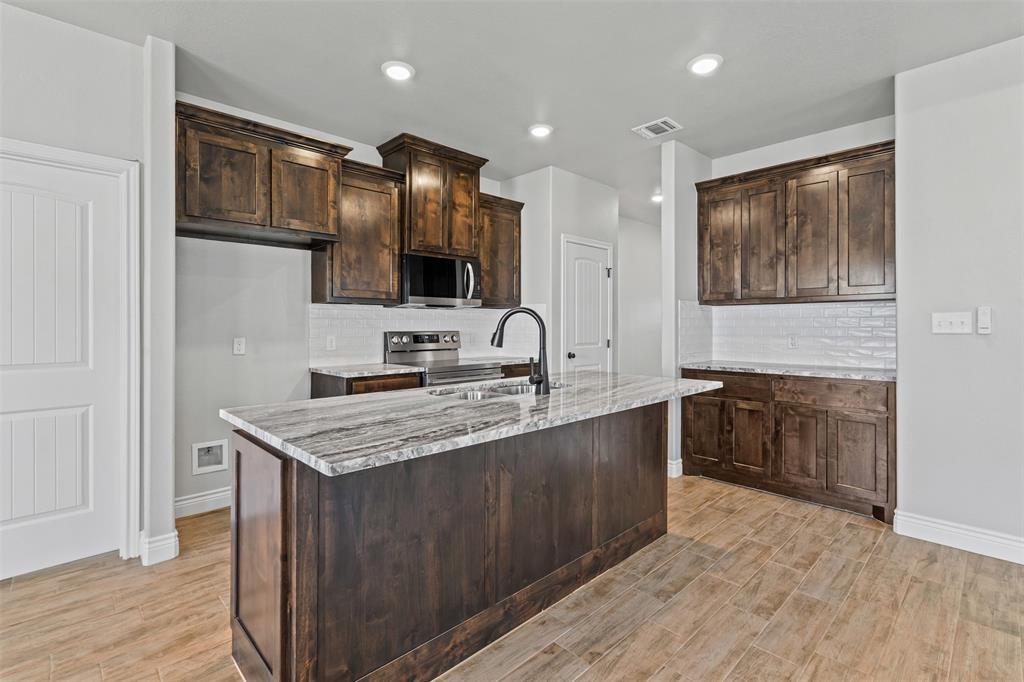 3400 Hilltop Road Granbury, TX 76048 - Photo 19 of 40 a kitchen with stainless steel appliances granite countertop a sink stove and cabinets