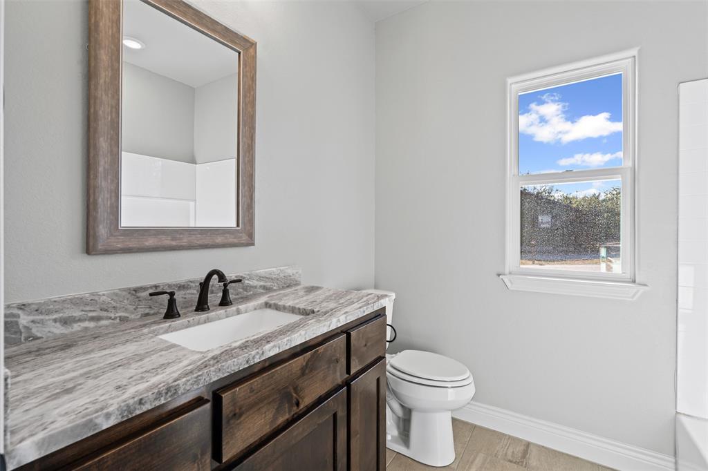3400 Hilltop Road Granbury, TX 76048 - Photo 31 of 40 a bathroom with a granite countertop sink mirror vanity and toilet