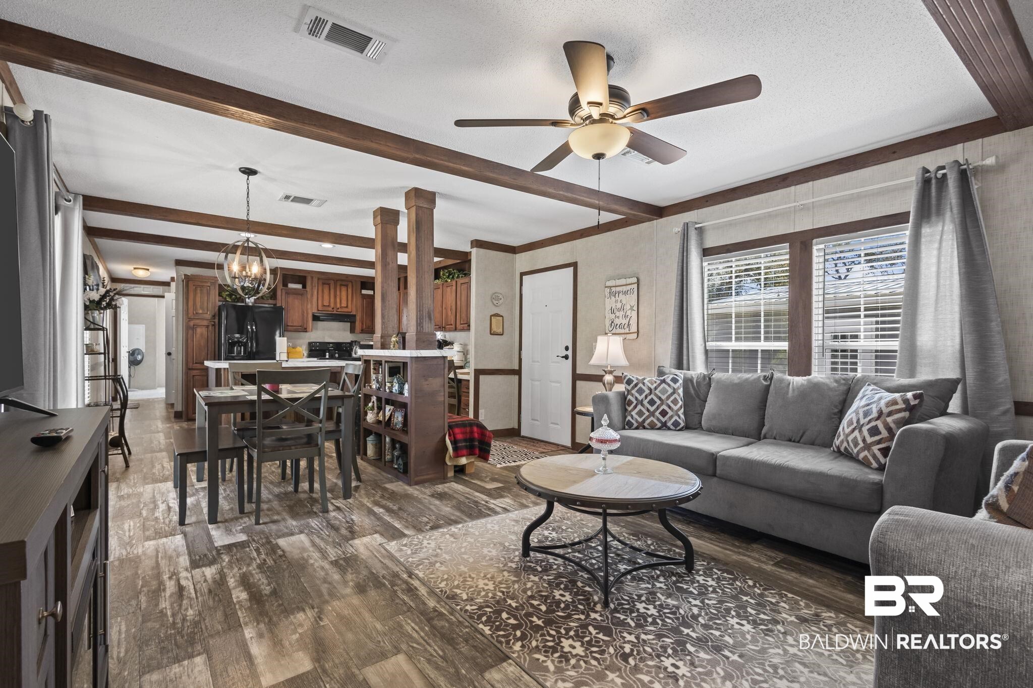 12960 7th Street Lillian, AL 36549 - Photo 6 of 25 Living area featuring ceiling fan with notable chandelier, visible vents, wood finished floors, and beam ceiling