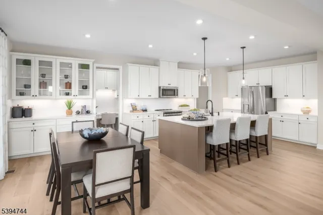 a kitchen with kitchen island a dining table chairs and white cabinets