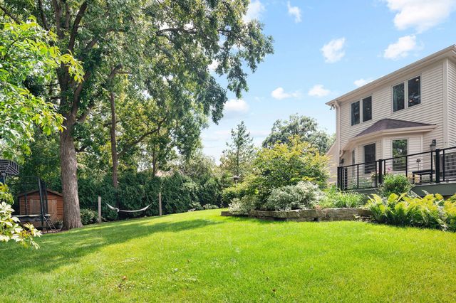 a view of a house with a big yard plants and large trees