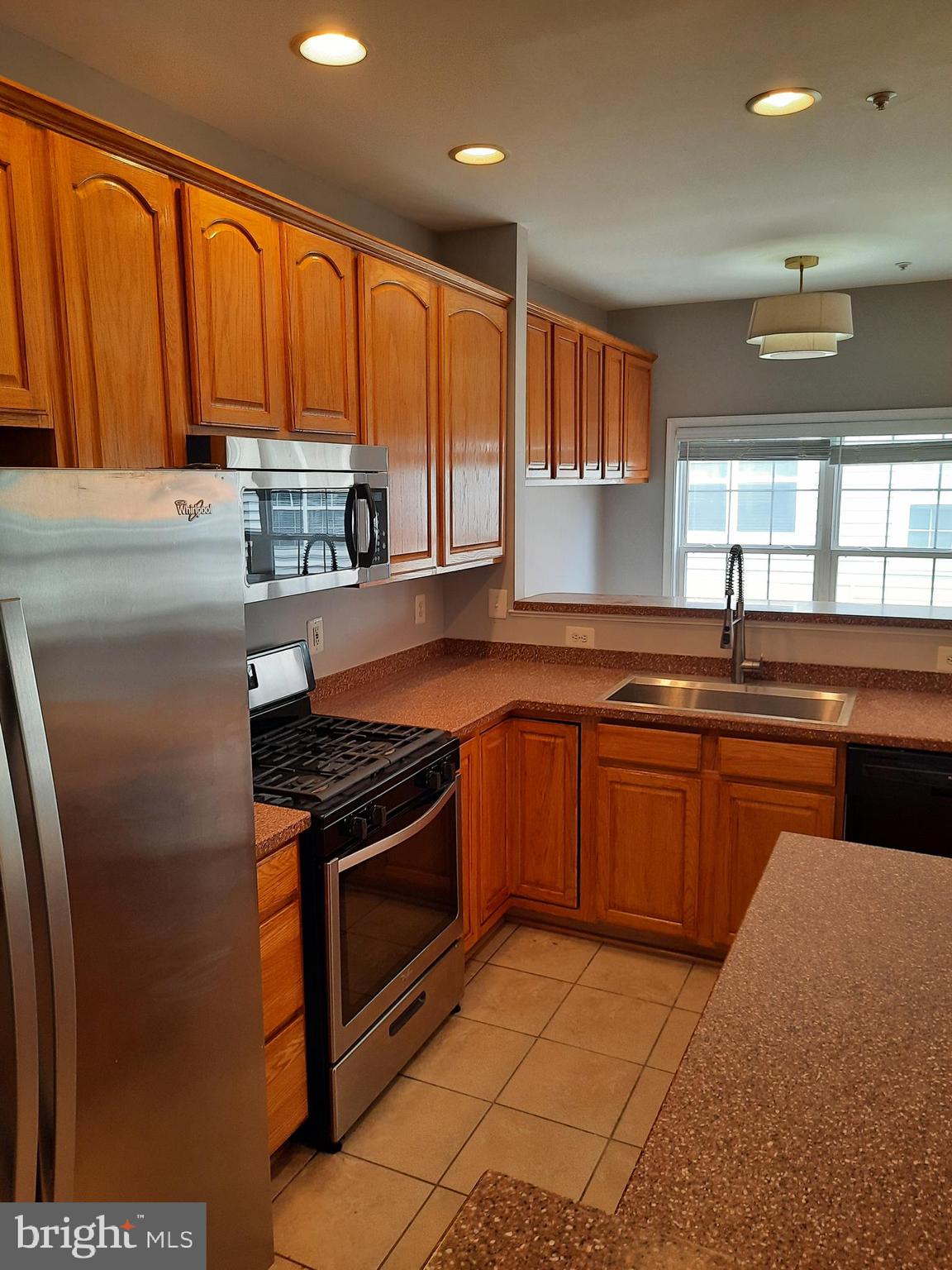 10258 Rutland Round Road, Unit 13 Columbia, MD 21044 - Photo 10 of 46 a kitchen with stainless steel appliances granite countertop a stove a sink and a microwave