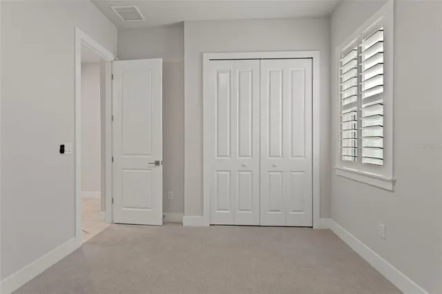 an empty room with ceiling fan and window