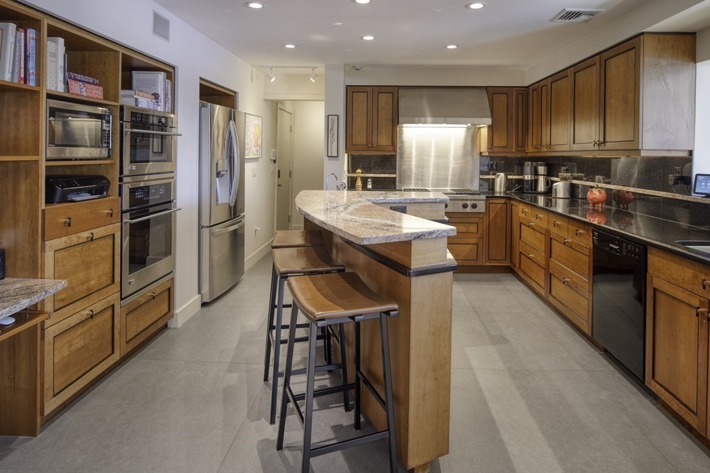 37 Beverly Road Arlington, MA 02474 - Photo 14 of 42 a kitchen with stainless steel appliances granite countertop a refrigerator a stove top oven a sink and a dining table with wooden floor