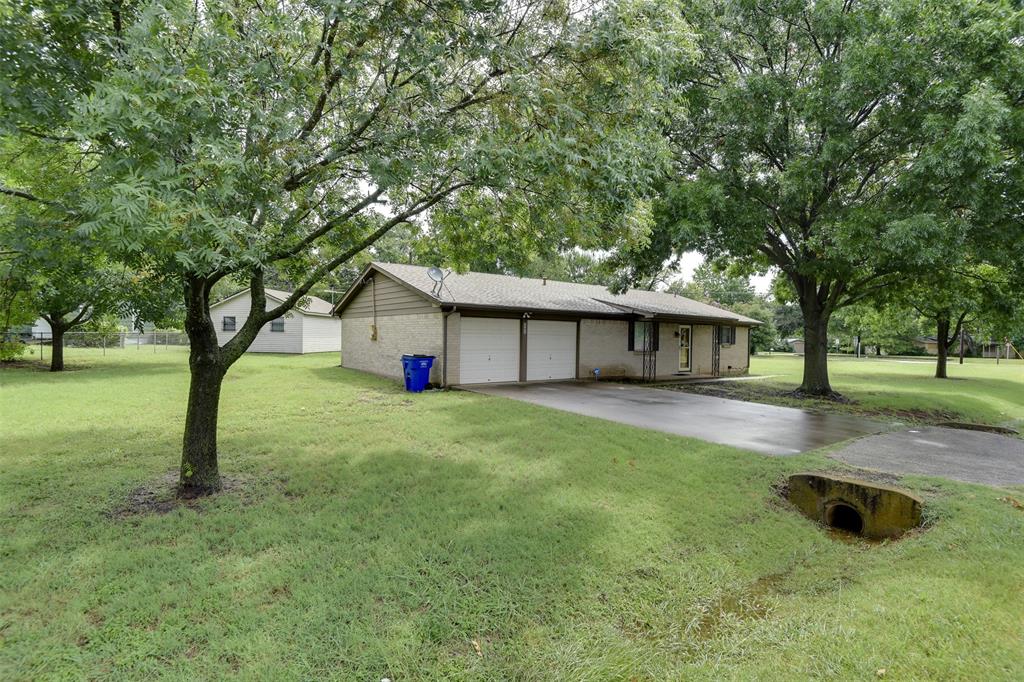 802 Cardinal Road Mansfield, TX 76063 - Photo 2 of 31 View of front of house featuring concrete driveway, an attached garage, a front lawn, brick siding, and view of wooded area