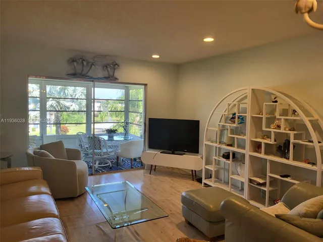 a living room with furniture a flat screen tv and a floor to ceiling window