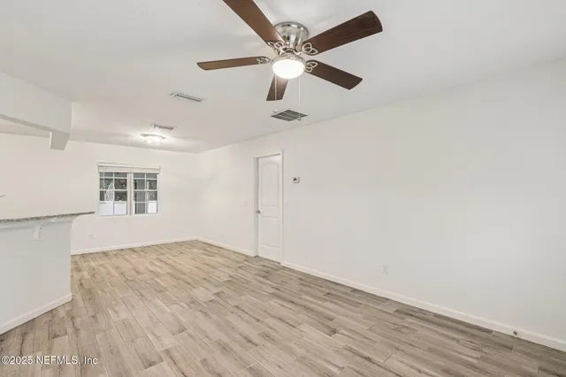a view of an empty room with window and wooden floor