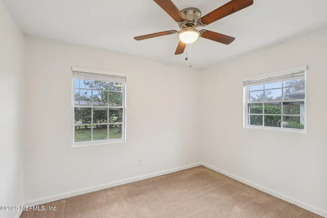 an empty room with a window and a fan