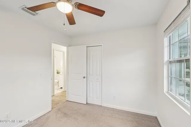 an empty room with windows and ceiling fan