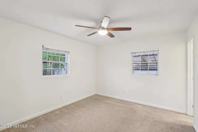 an empty room with a window and a ceiling fan