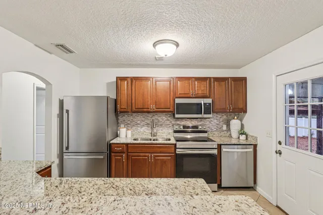 a kitchen with stainless steel appliances granite countertop a refrigerator stove microwave and sink