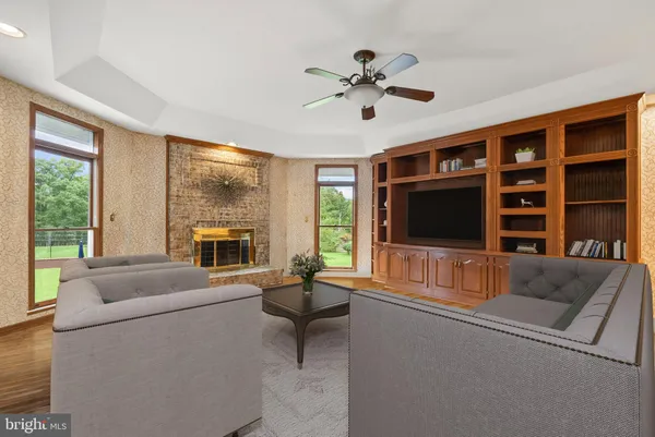 a living room with furniture floor to ceiling window hardwood floor and a flat screen tv