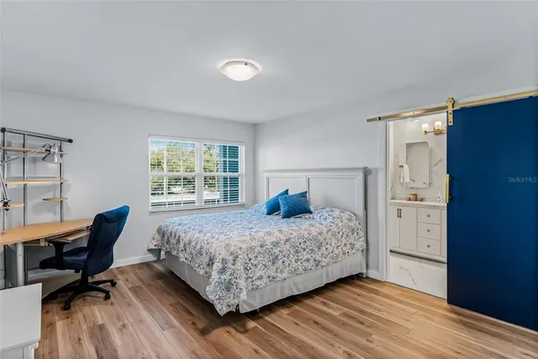 a bedroom with a bed and a dresser with wooden floor